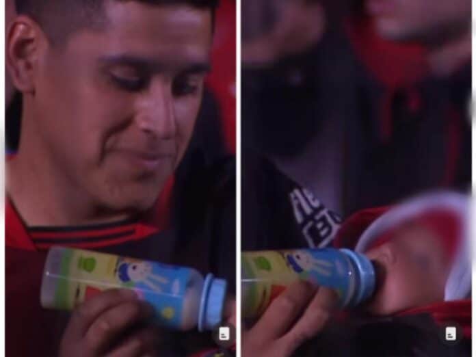 Un hincha del Colón alimentando a su bebé en el estadio, durante el partido
